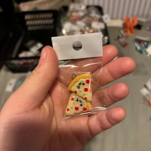 Pizzaformade örhängen - Unika örhängen formade som två pizzabitar med detaljer i rött, grönt och vitt. Perfekt accessoar för dig som älskar roliga smycken och vill sticka ut med en färgglad och lekfull stil.