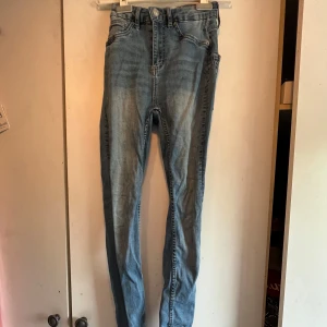 Blå skinny jeans från 157 - Säljer ett par klassiska blå skinny jeans från 157 i storlek XS. Jeansen har normalhög midja och dragkedja med knapp. Perfekta till vardags och lätta att matcha med olika toppar. Tyvärr fått ett hål framtill, därav priser 