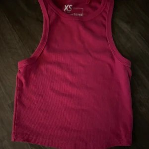 Rosa ribbad linnetopp - Säljer en enkel och snygg rosa ribbad linnetopp. Perfekt för varma dagar eller som layering-piece. Modellen är croppad och har breda axelband. Passar dig som gillar en avslappnad och trendig stil.