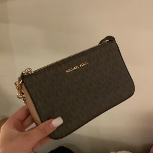 Brun Michael Kors handväska - Snygg brun äkta axelväska från Michael Kors med guldiga detaljer och kedjehandtag. Tillverkad i skinnliknande material och passar perfekt till vardag. Inga tydliga tecken på användning! Köpt för 1800.