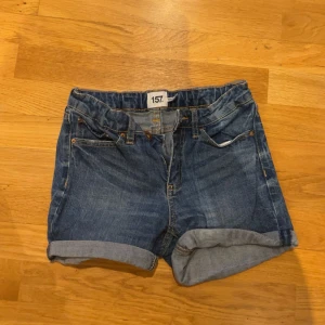 Blå jeansshorts från 157, storlek 160 - Snygga blå jeansshorts från 157 i klassisk modell med upprullade benslut och fem fickor. Perfekta för varma dagar och enkla att matcha med allt. Gjorda i slitstarkt jeanstyg med dragkedja och knapp framtill.