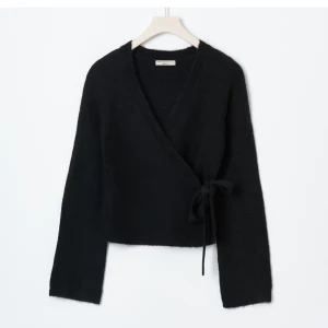 Svart omlottkofta  från Gina Tricot - Mysig svart omlottkofta från Gina Tricot med knyt i sidan och v-ringad hals. Koftan är stickad och har långa ärmar, jag säljer den då den inte längre kommer till någon användning för mig🩷helt slutsåld på hemsidan 