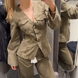shaped denim jacket - Säljer en olivgrön jeansjacka med markerad midja och vida ärmar. Jackan har v-ringning, stora bröstfickor med lock och knäpps med silvriga knappar framtill. Snygga sömdetaljer ger jackan en cool och unik look. Helt slutsåld säljer också på vinted med billigare frakt