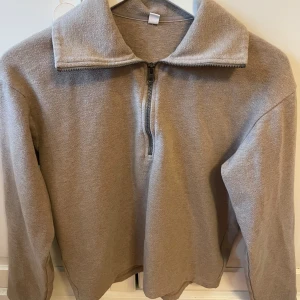 Beige fleece-tröja med half zip - Mysig beige fleece-tröja med hög krage och half zip-dragkedja framtill. Långärmad och i mjukt material som känns skönt mot huden.