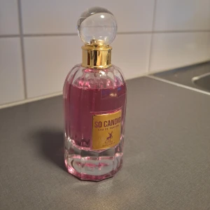 So Candid Eau de Parfum Maison Alhambra - So Candid från Maison Alhambra är en parfym för kvinnor med en söt, blommig doftprofil. Flaskan är elegant med rundad form, klar glas och guldig detalj vid halsen. Parfymen har en rosa nyans och en rund, genomskinlig kork. Doften har inslag av vit blomma, tuberos, citrus och mjuka, djuriska toner. (Ni ser mängd kvar)
