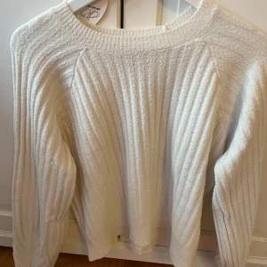 Vit ribbad stickad tröja - Supermysig vit stickad tröja med ribbat mönster och rund hals. Perfekt för kyliga dagar och enkel att matcha med jeans eller kjol. 