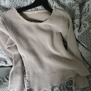 Beige stickad tröja med snörning - Säljer en chunky stickad tröja i beige med grov struktur och snygg snörningsdetalj i sidan. Tröjan har rund halsringning och långa ärmar, perfekt för lager-på-lager under kyliga dagar. Superenkel att styla till jeans eller kjol.