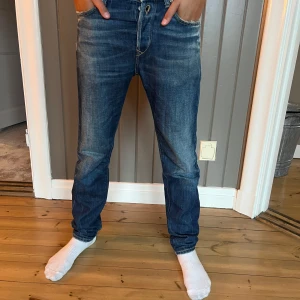 Replay jeans  - Snygga blå jeans med slitningar och tvättade detaljer. Modellen har en smal passform och klassisk femficksdesign. Perfekta för dig som gillar en modern och stilren look.