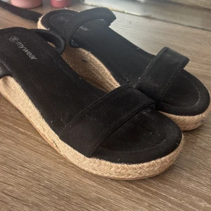 Svarta sandaler med platåsula från Mywear - Snygga svarta sandaler från Mywear med breda remmar i mocka och trendig platåsula i flätad jute. Perfekta för sommaren med sin öppna design och bekväma passform. Ger en chill vibe till alla outfits. Aldrig använda 