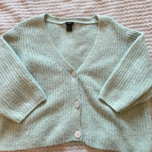 Ljusgrön kofta från Lindex - Supermysig ljusgrön kofta från Lindex med v-ringning och tre stora knappar framtill. Koftan är stickad och har en loose passform med lite kortare ärmar. Perfekt att slänga på sig när det är kyligt ute!