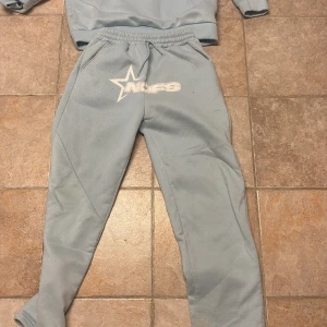 Ljusblå hoodie från NOFS med tryck - Säljer en ljusblå hoodie från NOFS med stor vit stjärnlogga och tryck på bröstet. Tröjan har huva, känguruficka och ribbade muddar. Perfekt för chill dagar eller när du vill ha en avslappnad stil.