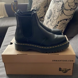 Svarta Dr. Martens Chelsea boots - Klassiska svarta Chelsea boots från Dr. Martens i skinn med elastiska paneler på sidorna och grov platt sula. Nyskick