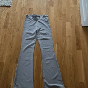 Ljusgrå bootcut byxor från 157, XS - Snygga ljusgrå bootcut byxor från 157 i stretchigt och mjukt material. De har hög midja och en clean look utan fickor eller synliga detaljer. Perfekta för dig som gillar en enkel men trendig stil.