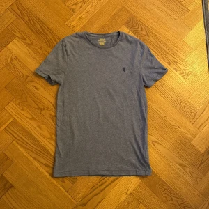Blå t-shirt från Polo Ralph Lauren - Snygg blå t-shirt från Polo Ralph Lauren med klassisk rund hals och broderad logga på bröstet. Modellen är slim fit och har korta ärmar. Perfekt basic-plagg med stilren design och mjukt bomullsmaterial.