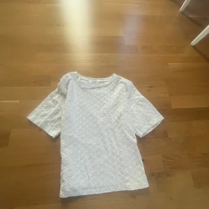 Vit spetsblus från MNG - Superfin vit blus från MNG med korta ärmar och broderade spetsdetaljer i hela tyget. Blusen har rund halsringning och ett romantiskt mönster som ger en söt och fräsch look. Perfekt till jeans eller kjol för en somrig vibe.