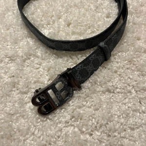 Burberry bälte grå - Snyggt bälte från Burberry i grått med monogrammönster och coolt BB-spänne i metall. Bältet har en stilren design med blommönster och är gjort i skinn med präglad yta. Perfekt för att lyfta vilken outfit som helst.