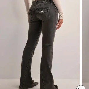 Grå bootcut true religon jeans - Snygga grå jeans med bootcut passform och coola fickdetaljer bak. Jeansen har låg midja, klassisk femficksdesign och kontrastsömmar. Perfekta för dig som gillar en avslappnad men trendig look.