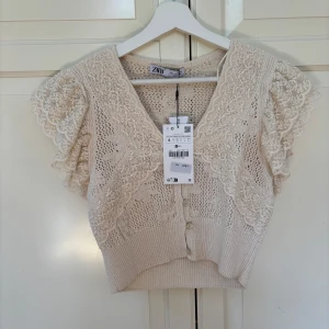 Beige spetsblus från Zara - Supersöt beige blus från Zara med virkade detaljer och volangärmar i spets. Aldrig blivit använd, helt ny med prislappen! Storlek s