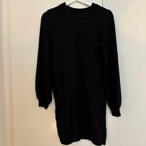 Svart stickad klänning från Object - Mysig svart stickad klänning från Object med rund halsringning och långa ärmar. Perfekt för lager-på-lager och enkel att styla med boots eller sneakers. Modellen är rak och har ribbade detaljer vid hals och ärmslut.