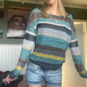  stickad tröja från Clockhouse - Säljer en luftig stickad tröja från Clockhouse i storlek XS. Tröjan har randigt mönster i blått, grått, brunt, gult och turkost. Den är långärmad och har en relaxed fit med bred halsringning. Perfekt för lager-på-lager och chill vår- eller sommarkvällar.