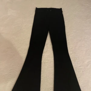 Svarta bootcut byxor - Snygga svarta byxor med bootcut-modell och utsvängda ben. De har en klassisk look och passar perfekt till sneakers eller boots. Byxorna är stilrena och har en hög midja som ger en modern siluett.