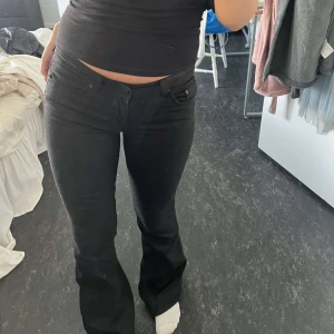Svarta bootcut jeans - Säljer ett par svarta jeans med bootcut-modell och låg midja. Sitter tajt över låren och släpper ut vid vaden för en snygg siluett. Klassisk femficksdesign och tillverkade i stretchig bomullsdenim. Perfekta till sneakers eller boots.