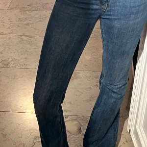 Blå bootcut jeans i storlek 36 - Snygga blå bootcut jeans i klassisk modell med normal passform. Jeansen har en lätt utsvängd benvidd och är tillverkade i mjukt denimtyg. Perfekta för dig som gillar en retroinspirerad look med moderna vibbar.