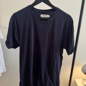 Marinblå t-shirt från Ljung - En stilren marinblå t-shirt från Ljung med klassisk rund hals och korta ärmar. Tillverkad i mjuk bomull som känns skön mot huden. Perfekt basic-plagg att matcha med jeans eller shorts.