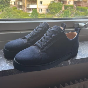 Mörkblå mocka sneakers från Louboutin - Snygga mörkblå sneakers från Christian Louboutin i mocka med klassisk röd sula och diskret logga på insidan. Skorna har rund tå, platt sula och snörning. Perfekta för dig som vill ha en lyxig och stilren look med streetkänsla. Hör av dig vid frågor eller funderingar!