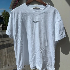 Acne Studios T-Shirt Vit - Vit Acne Studios T-shirt i storlek M, med boxy fit för en avslappnad och modern silhuett. I mycket fint skick – sparsamt använd, utan fläckar eller hål.