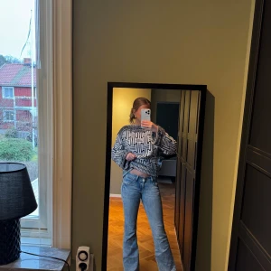 Blå bootcut jeans med broderade fickor - Säljer ett par vintage ljusblå bootcut jeans med snygga broderade detaljer på bakfickorna och knappar. Jeansen är lågmidjade och sitter väldigt fint.