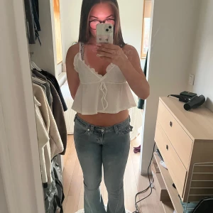 Vit volangig linnetopp från SHEIN - Supersöt vit linnetopp från SHEIN med volangkant, smala axelband och knyt framtill. Toppen är croppad och har en lätt rynkad struktur i tyget som ger en chill och somrig vibe. Perfekt till jeans eller kjol för en fräsch look.