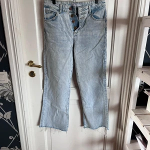Ljusblå raka jeans från Zara - Ljusblå jeans från Zara med raka ben och råa, fransiga benslut. Hög midja och klassisk femficksmodell med knappar i gylfen. Jeansen är i ett mjukt bomullsmaterial och har en avslappnad, trendig vibe. Avklippta då dom var för långa, är 157 och dom är bra längd på mig