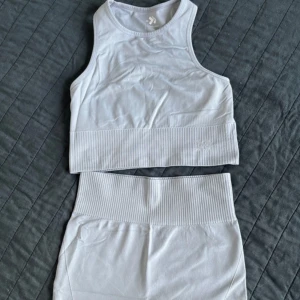 Blå ribbade set XS/S - Snygga blåa träningstights-shorts och top från 157 i storlek XS/S. De är högmidjade med bred ribbad linning och ribbade detaljer längs benen. Materialet är stretchigt och passar perfekt för träning eller chill. Enkel, stilren design utan mönster.