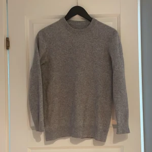 GardeGrisch tröja  - En enkel och stilren grå stickad tröja från GardeGrisch .  Tröjan har ribbade muddar vid ärmslut och nederkant, vilket ger en snygg och klassisk look. Perfekt att matcha med jeans eller kjol för en chill vibe.