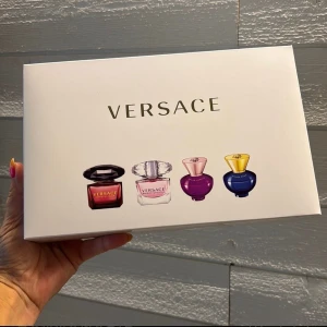 Versace parfymset presentbox - Lyxigt parfymset från Versace med fyra olika dofter i miniflaskor. Flakongerna är i färgerna röd, rosa, lila och blå med eleganta lock i svart, silver, rosa och guld. Perfekt för dig som vill testa flera ikoniska Versace-parfymer.