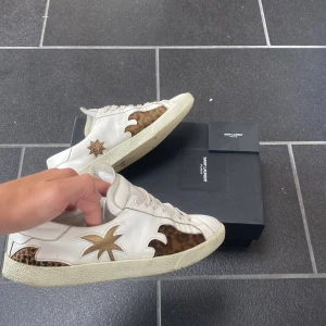 Saint Laurent sneakers med leoparddetaljer - Säljer nu dessa sjukt feta saint Laurent skor som är även är sällsynta. De är storlek 42 men passar även 43. De har märken på undersidan av skon. (Syns inte när man har på sig skorna). Pyttelite smutsiga också men går att ta bort med rätt medel. Hör av dig vid funderingar!🙌