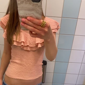 Rosa volangtopp från Lindex XS - Supersöt ljusrosa topp från Lindex i smockat tyg med volangdetaljer över axlarna. Toppen är i Storlek Xs men passar även S då den ör stretchig.