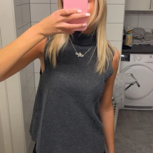 Mörkgrå ärmlös polotopp Zara - Snygg mörkgrå polotopp med ärmlös design och hög krage 