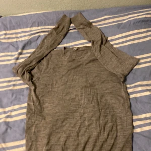 Grå stickad tröja från Uniqlo - Säljer en enkel och stilren grå stickad tröja från Uniqlo i storlek S. Tröjan har rund hals, långa ärmar och ribbade muddar vid ärmslut och nederkant. Perfekt för dig som gillar minimalistisk och clean look.