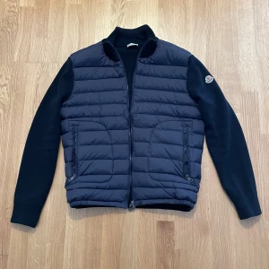 Moncler Cardigan - Säljer denna fina Moncler Cardigan i färgen - Navy Blue. Jackan är använd under ett tillfälle och är väl omhändertagen. Säljer den eftersom den passar inte mig som jag vill!