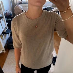 Beige stickad T-shirt med kort ärm - Snygg beige stickad T-shirt med rund hals och korta ärmar. 