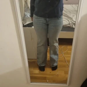 Perfect Jeans bootcut från Gina Tricot - Säljer ett par ljusblå bootcut jeans från Gina Tricot, modell Perfect Jeans. Klassisk femficksdesign, låg midja och raka ben med lätt utsvängd passform. Jeansen är i bomull och har snygga detaljer med dubbla knappar framtill. Med lätta rämsor på slutet av benen