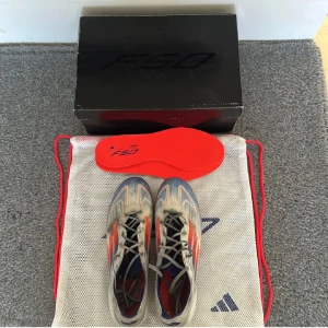Adiddas f50 elite skor  - Säljer ett par Adidas F50 Elite FG fotbollsskor i  vitt Med blå detaljer.                                                               Storlek 41/3.                                                                   Skick 8/10, finns märken av användning men skorna har anvends sparsamt.                                     Tillbehör allting original, box extra sulor påse osv                                Pris, 600 kan du gå ner vid snabb affär 🕰️✅     