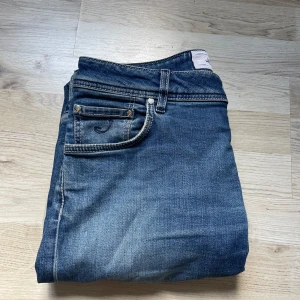 Blå jeans från Jacob Cohen, storlek 31 - Snygga blå jeans från Jacob Cohen med klassisk femficksdesign och kontrastsömmar. Jeansen har en normal passform och är tillverkade i mjukt bomullsmaterial. Bak finns en beige patch med logga. Perfekt för dig som gillar stilrena och tidlösa jeans.