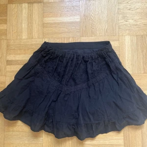 Svart volangkjol med broderi - Säljer en svart kortkjol med volanger och broderade blommor upptill. Kjolen har en mjuk och luftig känsla, med snygga detaljer som ger den extra karaktär. Perfekt för dig som gillar en feminin och chill stil. Aldrig använd. Skriv vid minsta fråga!💕💕