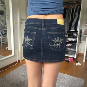 Mörkblå lågmidjad jeanskjol  - Säljer en mörkblå lågmidjad minijeanskjol från Kappahl med snygga guldfärgade detaljer och dragkedjor framtill. Är i helt nytt skick. OBS får inte igen dragkedjan för att den är för liten på mig