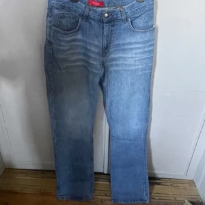Blå jeans från Sand Jeans straight fit - Säljer ett par klassiska blå jeans från Sand Jeans med straight fit och normal passform. Storlek 40 / M. Jeansen har fem fickor, bälteshällor och knappgylf. Materialet är slitstarkt denim i bomull och färgen är ljusblå med snygga tvättade detaljer framtill.