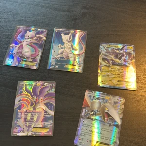 Pokémon EX Holo Collection - Samling av fem glittrande Pokémon EX-kort: Mewtwo, Thundurus, Malamar och Skarmory. Perfekt för dig som älskar att samla, spela eller bara vill ha riktigt snygga kort att visa upp för vänner. Färgstarka motiv och coola effekter gör dessa till ett måste för alla Pokémon-fans!