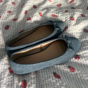 Blå jeans ballerina med rosett - Säljer ett par snygga ballerina skor i blått jeanstyg med rund tå och en söt rosett framtill.  Passar till både jeans och kjol. Storlek 38, endast använd en gång